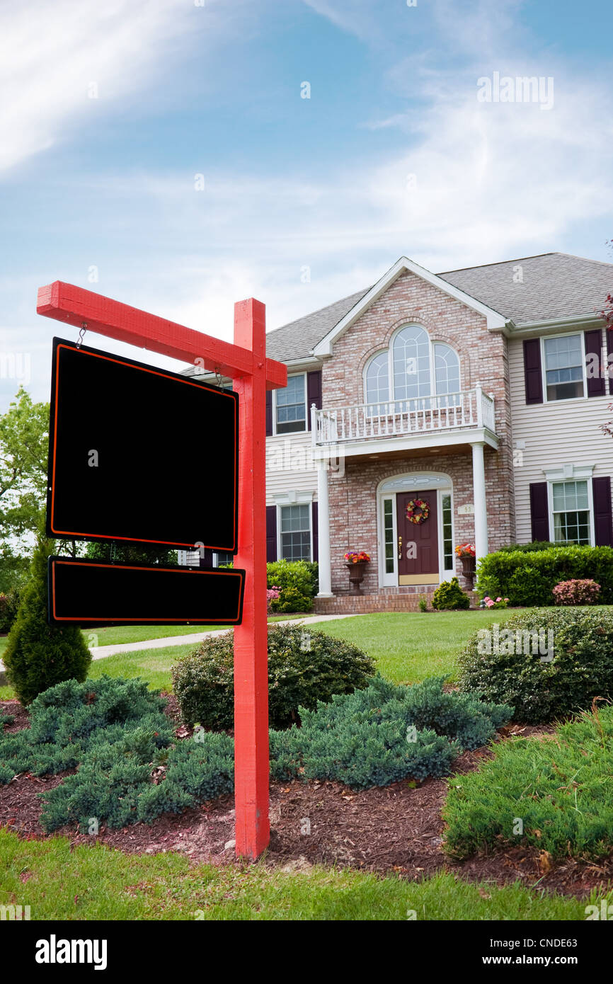 Una bella casa di lusso con un fustellato in vendita il segno inviato nella parte anteriore. Abbondanza di spazio copia sul vuoto segno per il tuo testo. Foto Stock