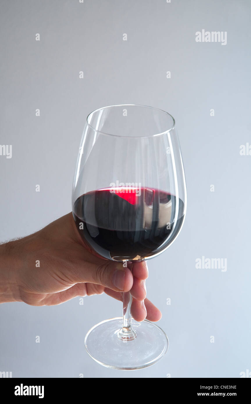 Mano d'uomo con in mano un bicchiere di vino rosso Foto stock - Alamy