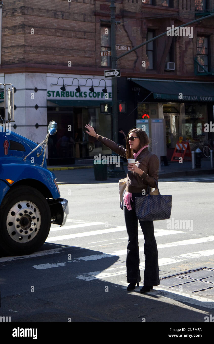 Donna salutando con taxi su New York City angolo di strada, Upper West Side, davanti di Starbucks Foto Stock