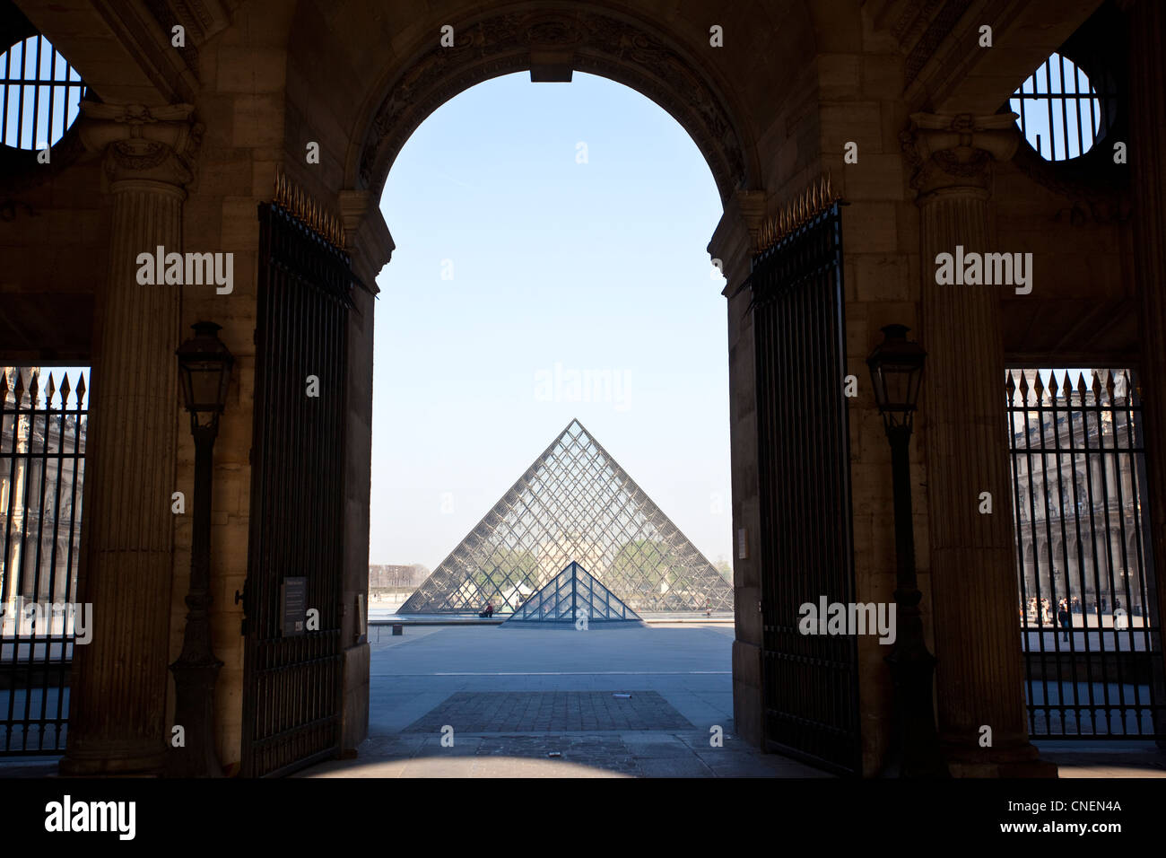 La piramide di vetro visto attraverso un arco tra il Palais du Louvre verso il Musée du Louvre, Paris, Francia. Foto Stock