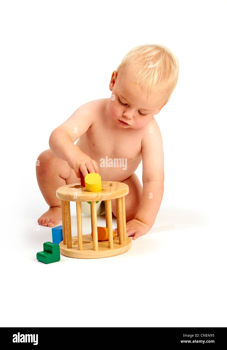 Un simpatico baby boy toddler concentrando la riproduzione con un selezionatore di forma toy isolato su uno sfondo bianco Foto Stock