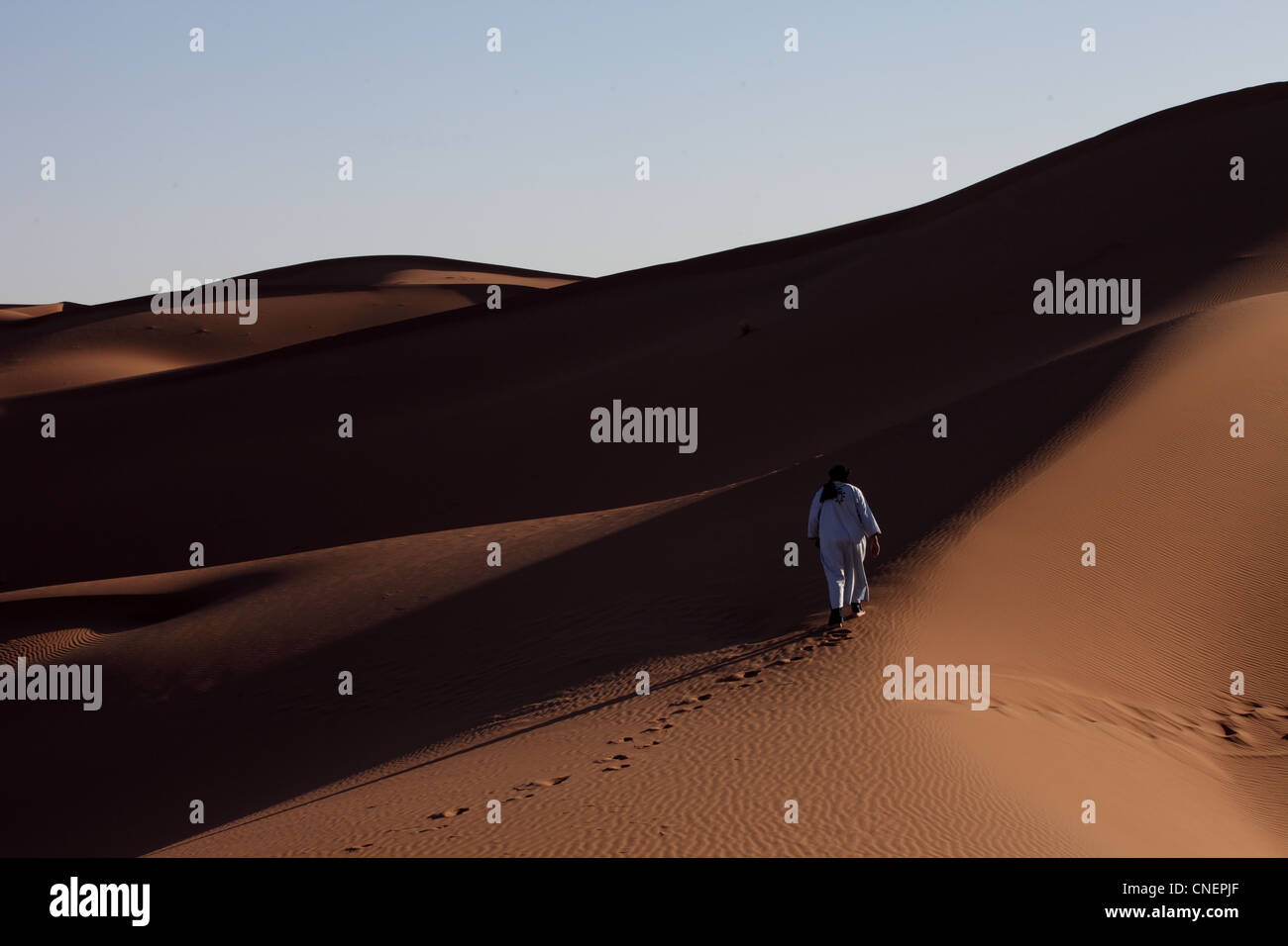 Marocchino arabo Berbero in abito tradizionale a piedi nei Chegaga dune del deserto del Sahara nel sud del Marocco Foto Stock