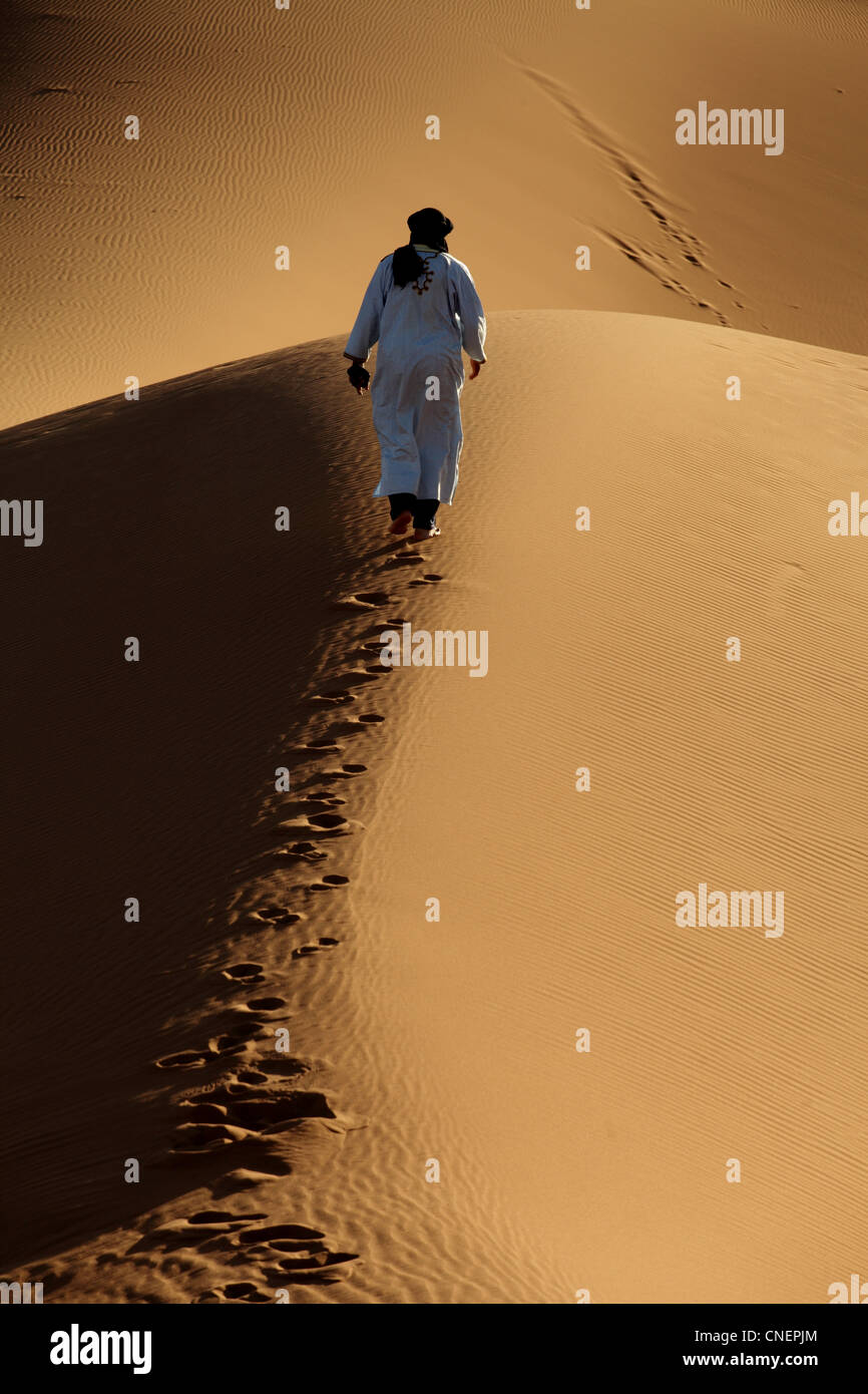 Marocchino arabo Berbero in abito tradizionale a piedi nei Chegaga dune del deserto del Sahara nel sud del Marocco Foto Stock