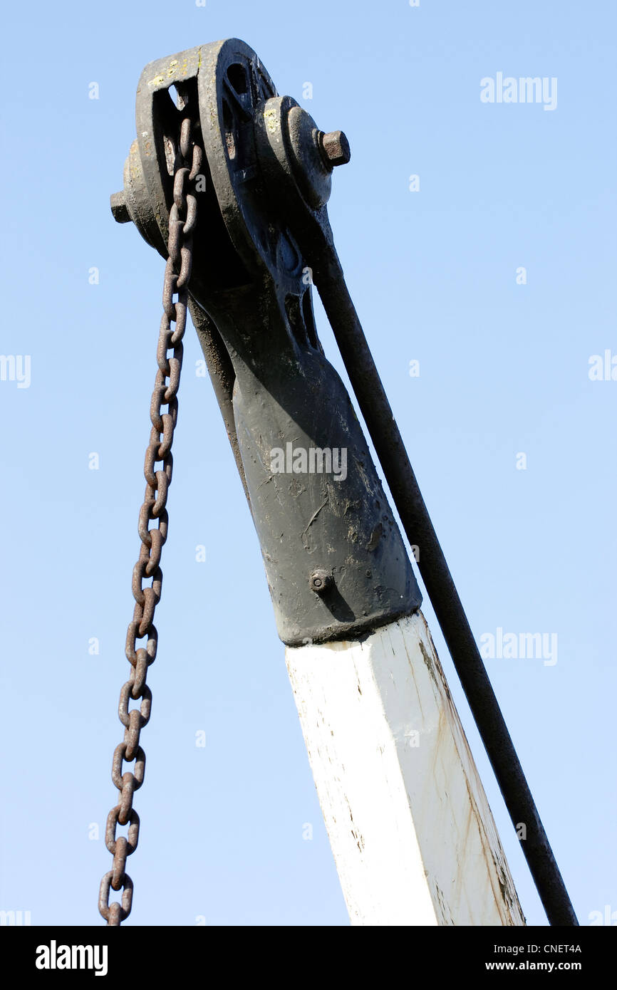 Una vecchia gru industriali con la catena di un ingranaggio di sollevamento. Foto Stock