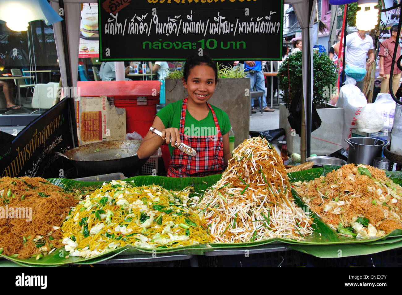 Donna che serve noodles in cucina di strada in stallo, New Phetchaburi Road, Ratchathewi District, Bangkok, Thailandia Foto Stock