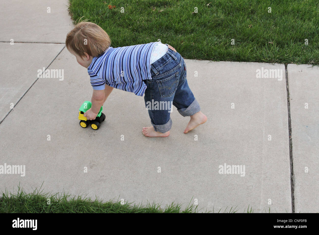 Un bimbo di 2 anni spingendo un giocattolo carrello. Foto Stock
