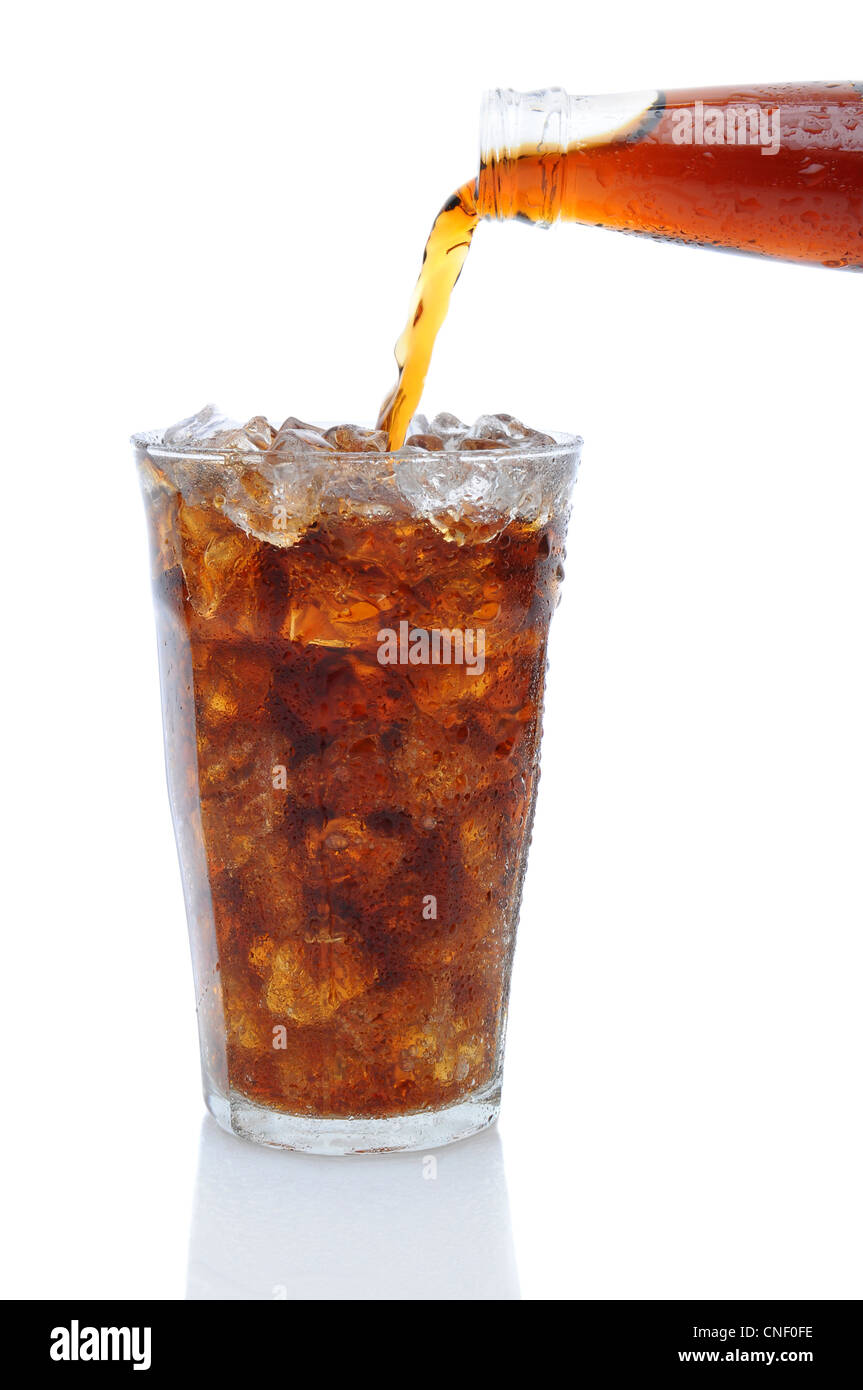 Una bottiglia di coca cola soda versando in un bicchiere riempito con cubetti di ghiaccio su uno sfondo bianco con la riflessione. Foto Stock