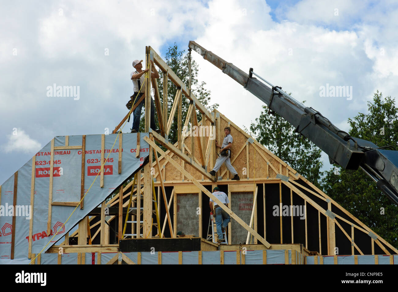 Operaio edile inquadrando il tetto di una casa di campagna con l aiuto di una gru nel paese del Quebec, Canada Foto Stock