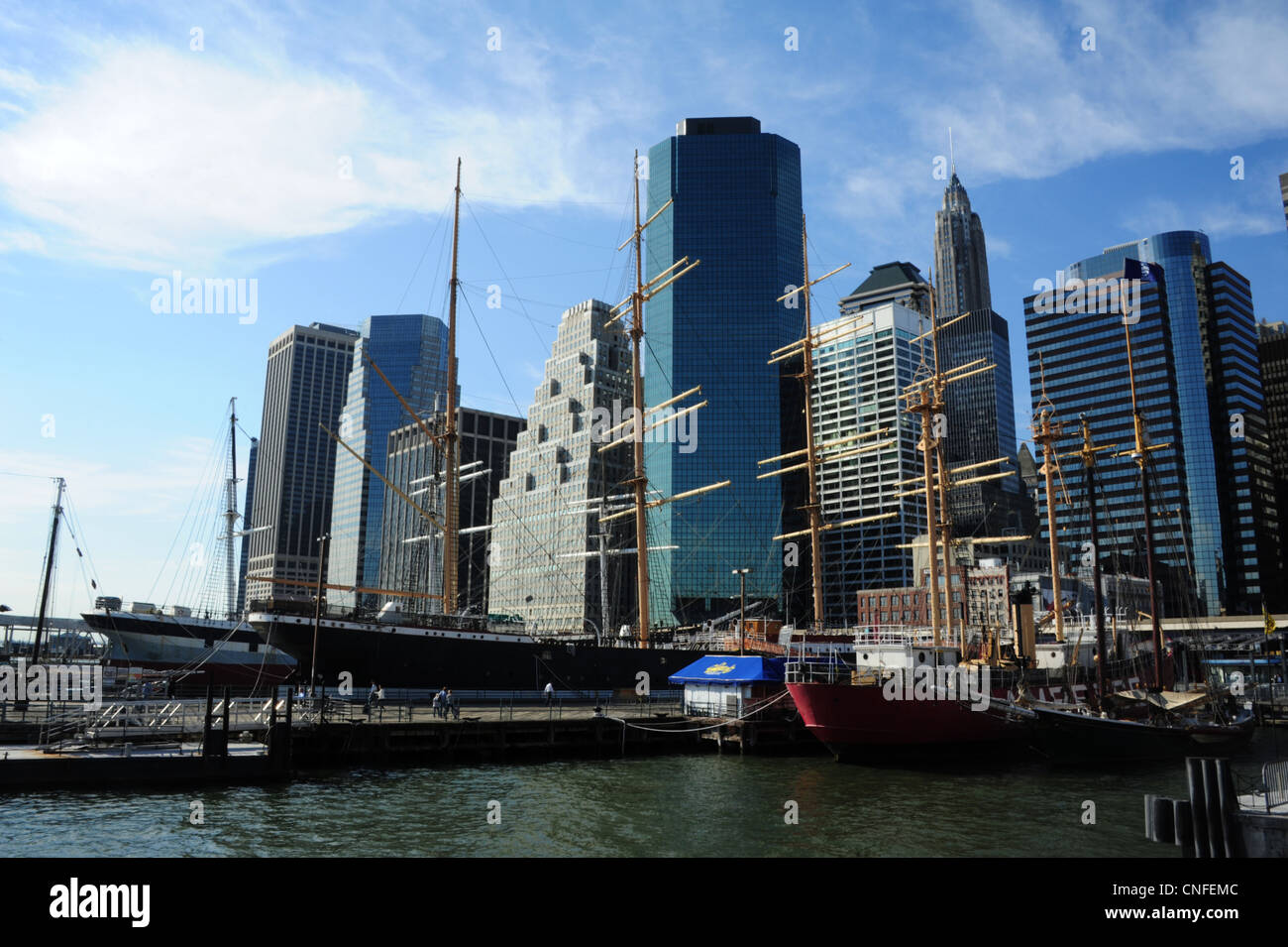 Blue sky view, verso il quartiere finanziario di grattacieli, le navi a vela ormeggiata acque verde South Street Seaport Museum di New York Foto Stock