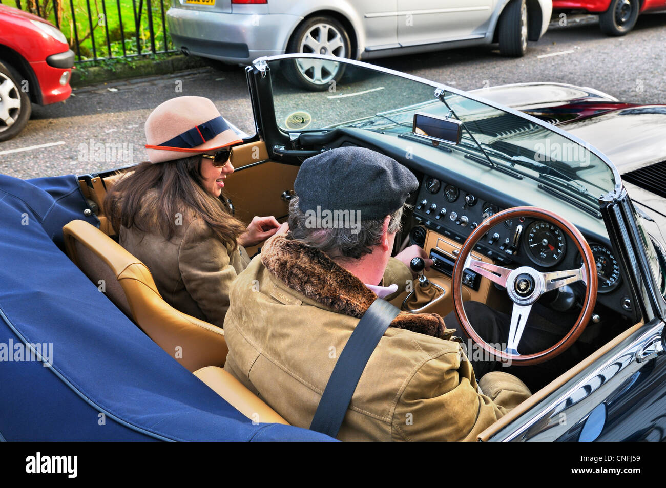 Lady e gent seduti in un E-type Jaguar auto classica, London, England, Regno Unito Foto Stock