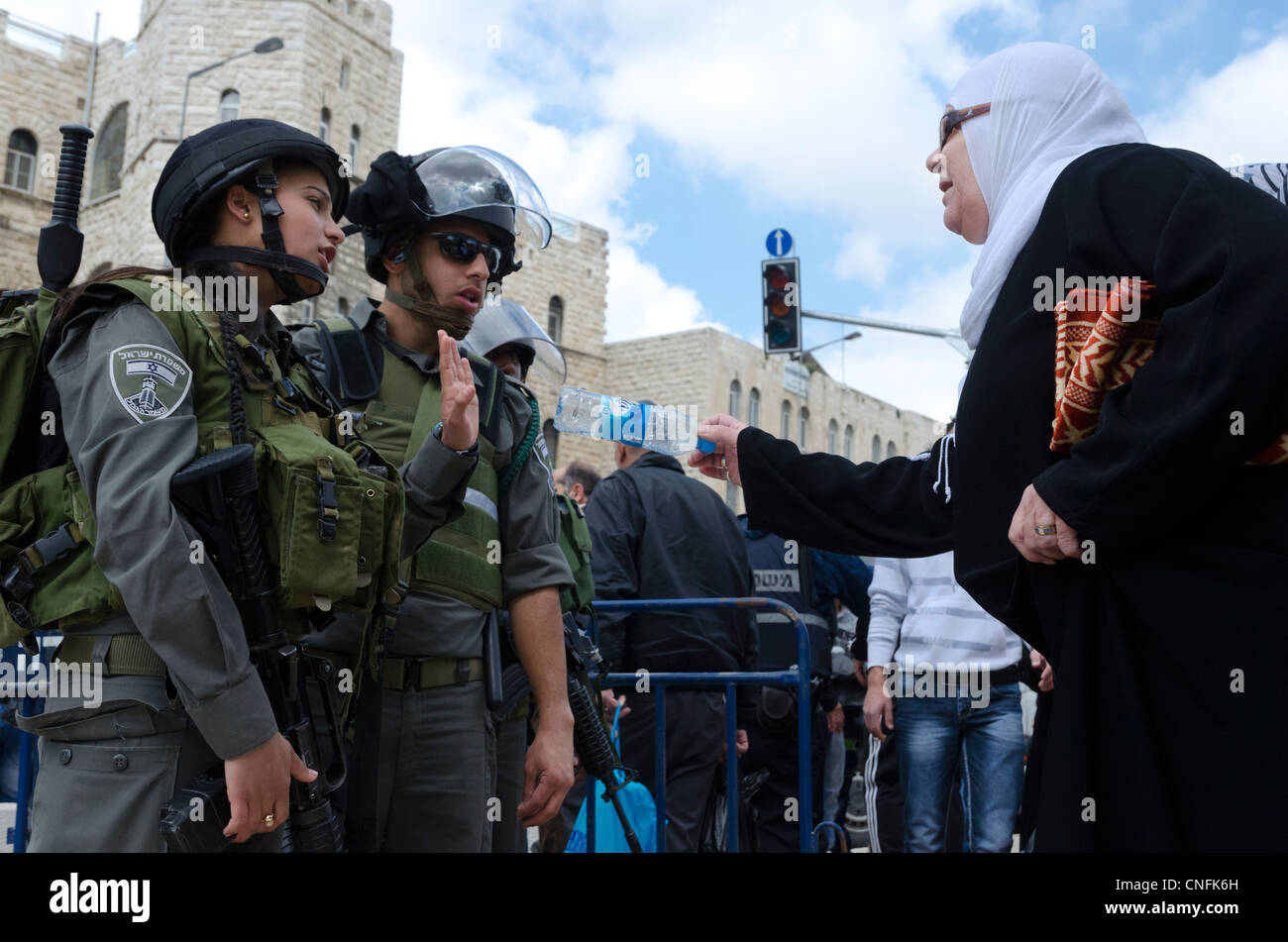 Maschio e femmina di pattuglia di confine di fronte a una donna Plestinian sulla terra il giorno. Porta di Damasco. Israele. Foto Stock