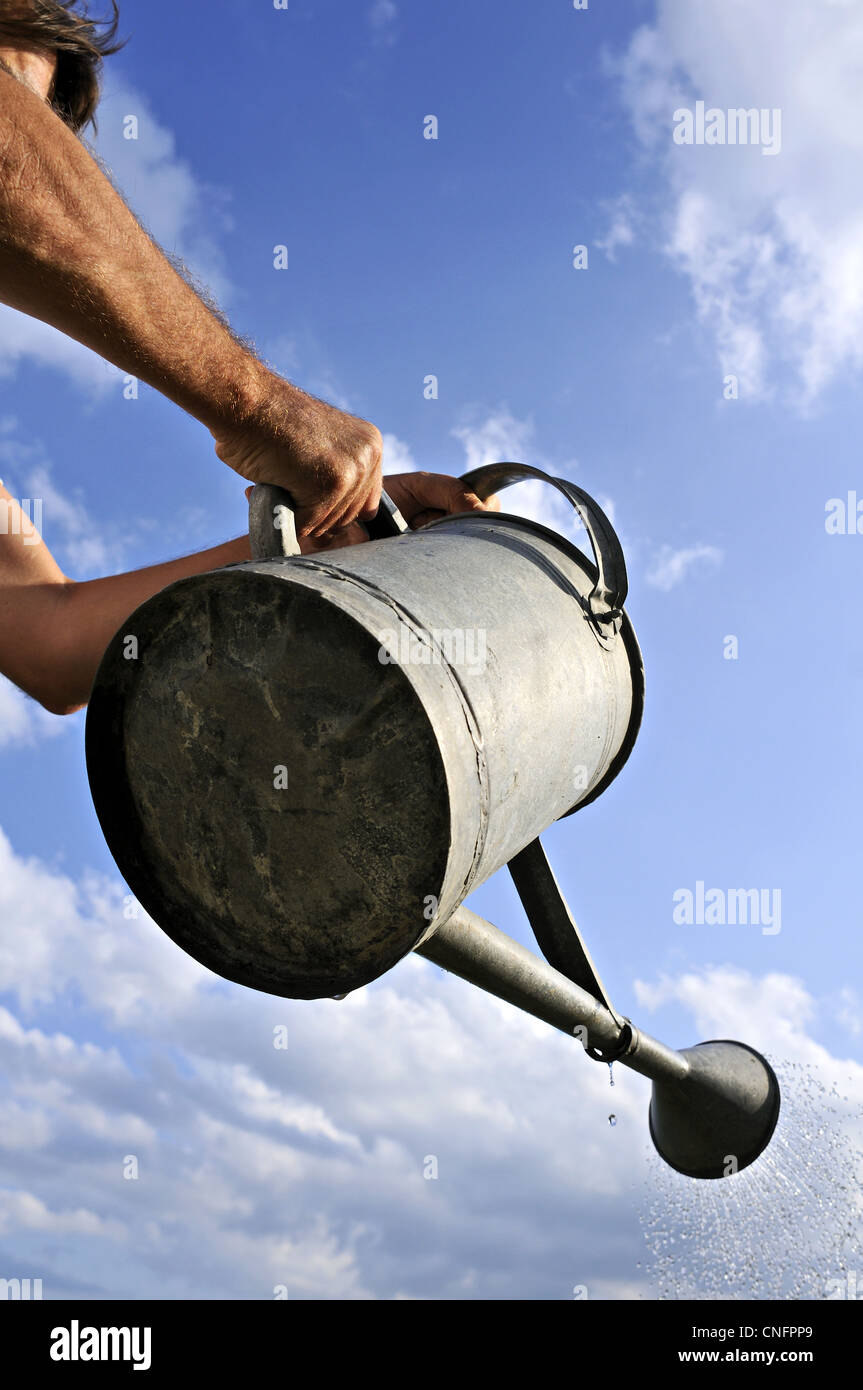 Irrigazione uomo con un vecchio metallo può Foto Stock