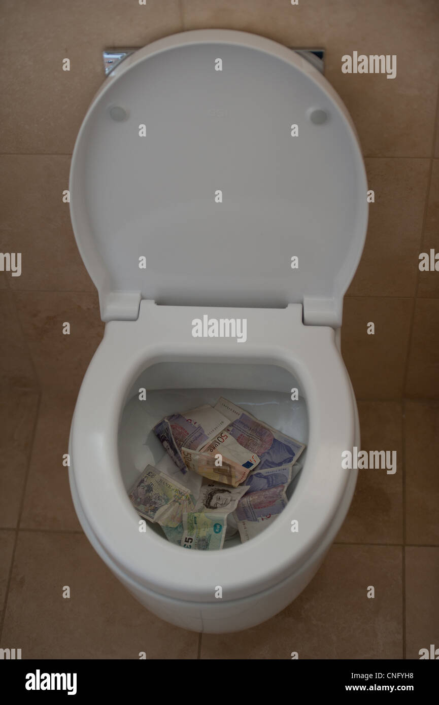 Soldi andando giù per la toilette con riguardo alla crisi finanziaria e di economia mondiale Foto Stock
