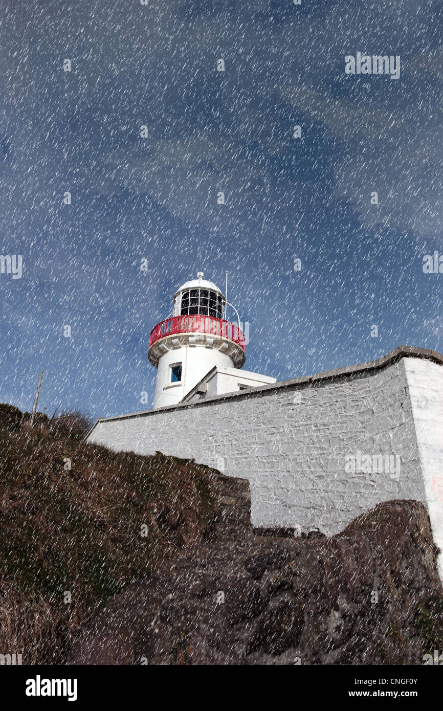 Faro durante una tempesta di pioggia sulle rocce a youghal nella contea di Cork in Irlanda, Foto Stock