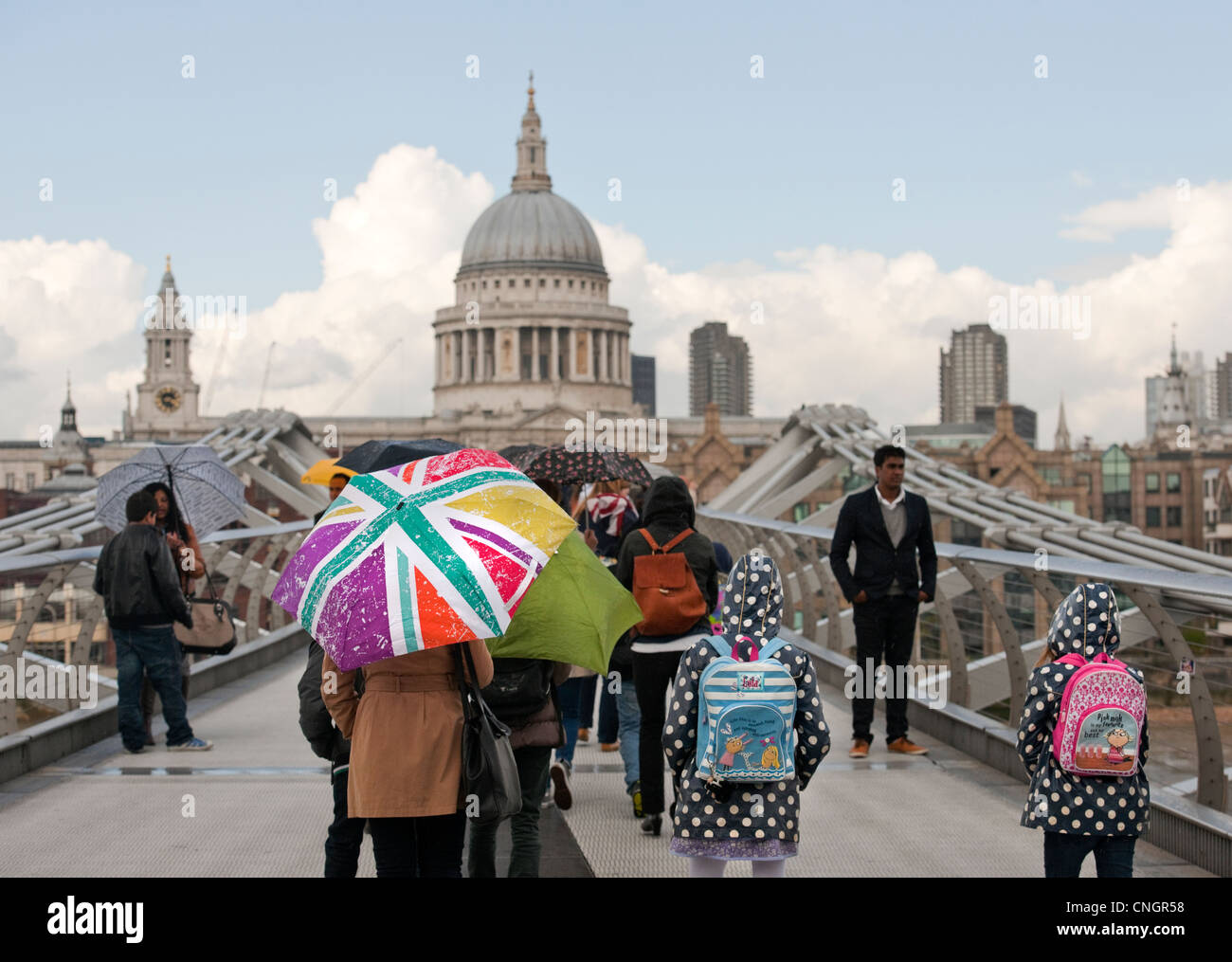Millennium Bridge City di Londra dopo una molla leggera doccia i turisti amano camminare verso la Cattedrale di St Paul e sotto gli ombrelloni Foto Stock