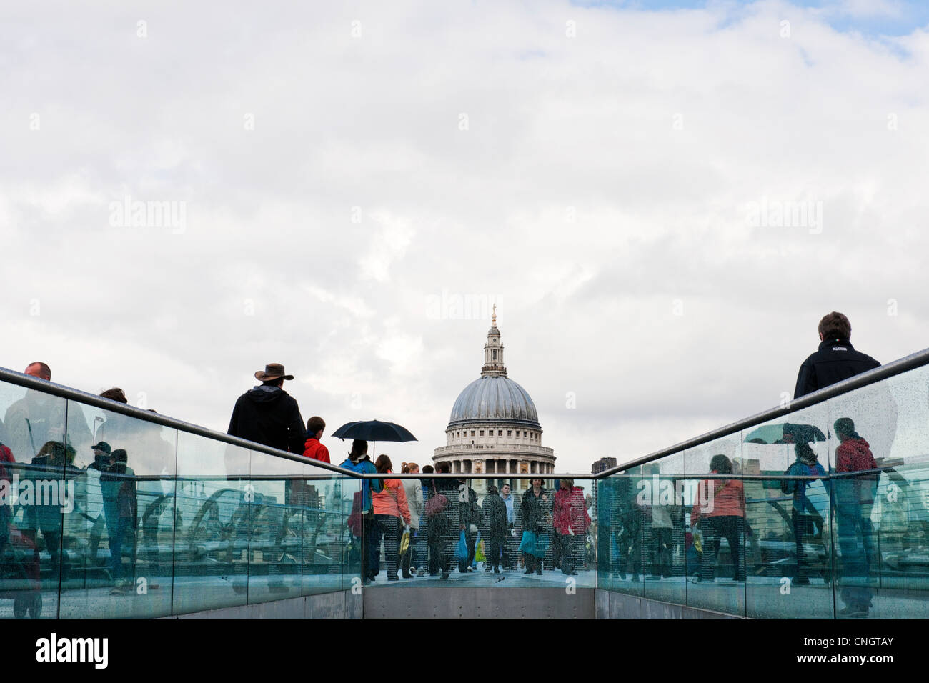 South Bank di Londra agli inizi della primavera dopo una doccia a pioggia. Le persone che attraversano il Millennium Bridge verso la Cattedrale di St Paul Foto Stock