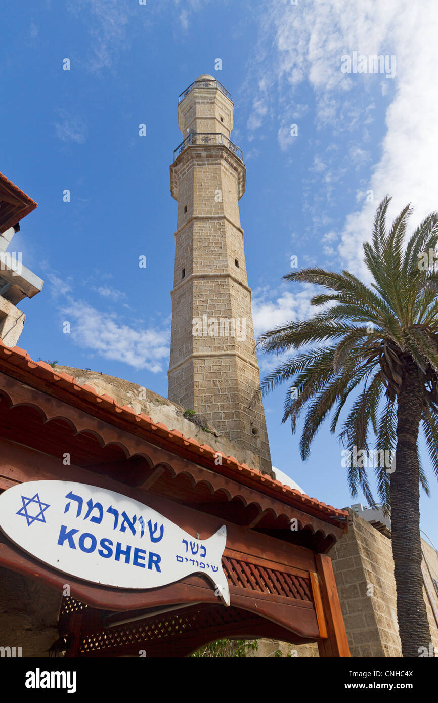 Minareto musulmano visto accanto a un segno per un ebreo Cascer mercato nella Vecchia Jaffa, Tel Aviv, Israele Foto Stock