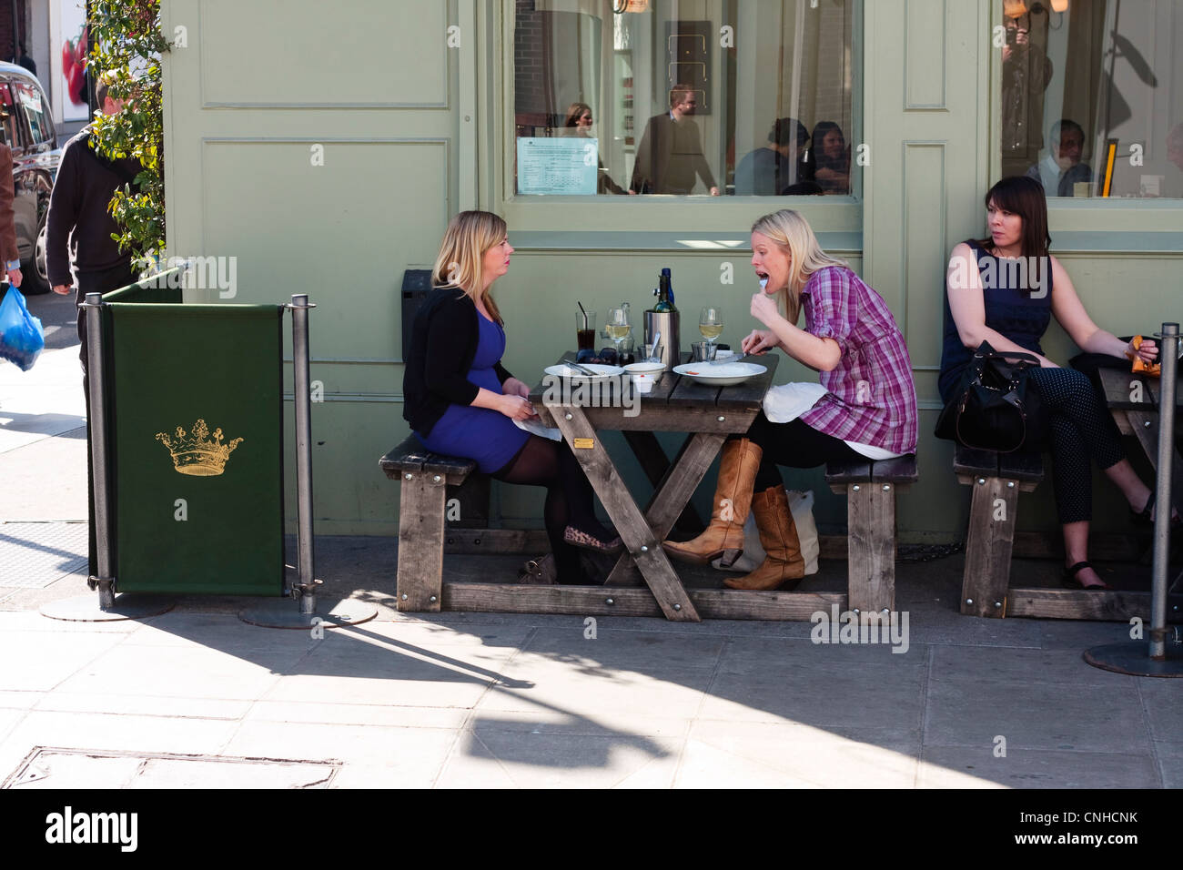 Due femmine seduta al di fuori di un pub di mangiare il pranzo, London, Regno Unito Foto Stock