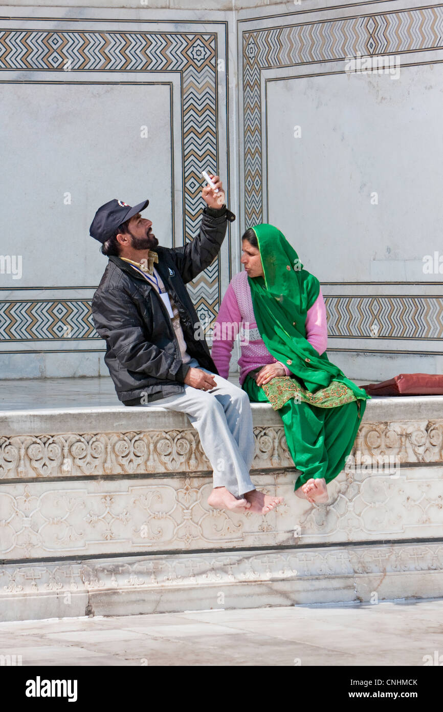 Agra, India. Taj Mahal. Indian giovane, uomo guardando una foto sul suo telefono cellulare. Foto Stock