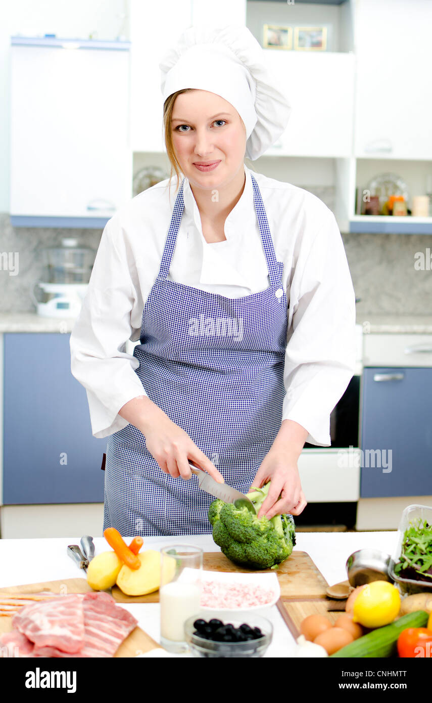 Attraente capo cuoco preparare cibi, tagli broccoli Foto Stock