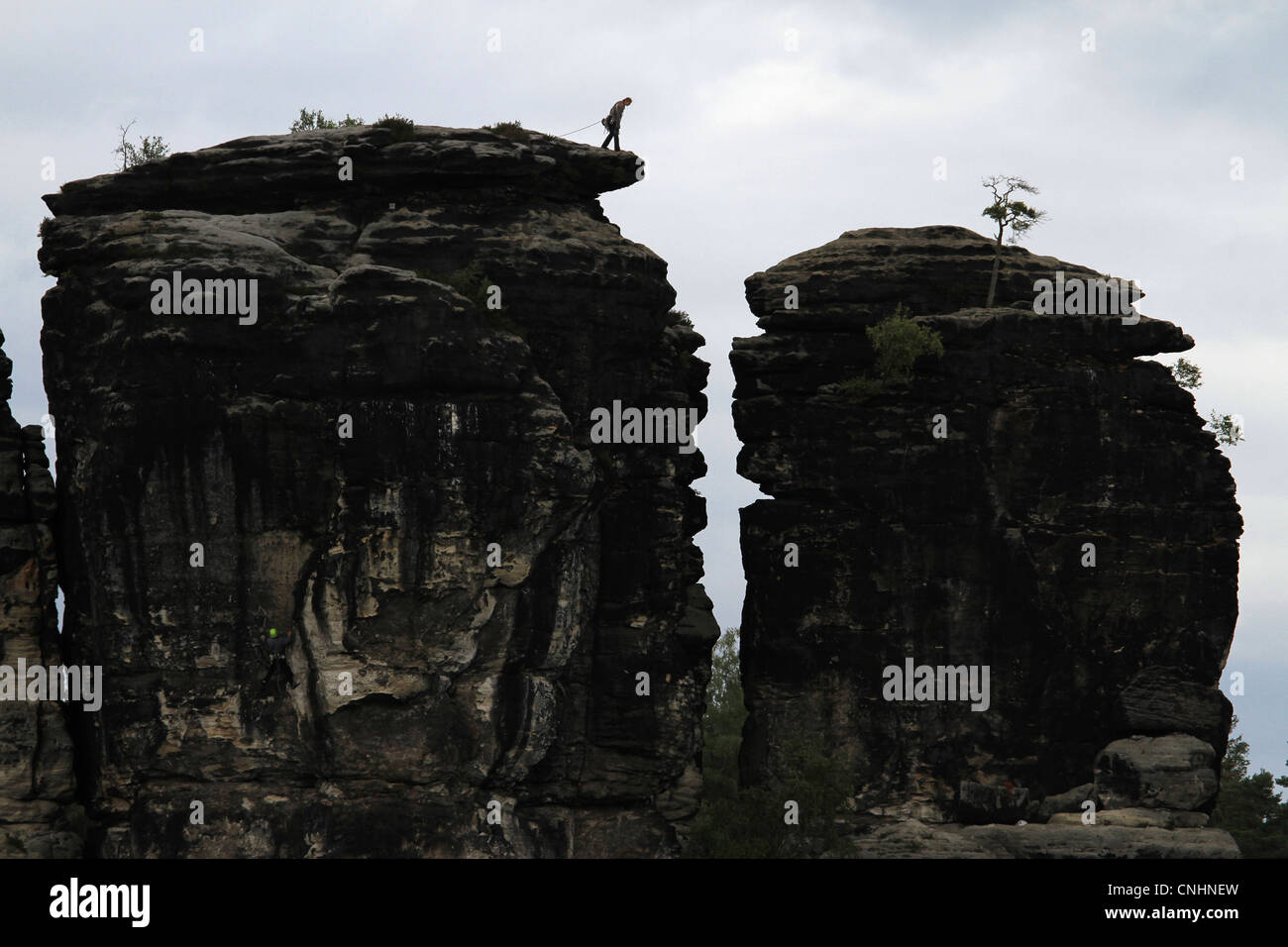 Una persona si prepara a rappel verso il basso una formazione di roccia, Svizzera Sassone, Bassa Sassonia, Germania Foto Stock