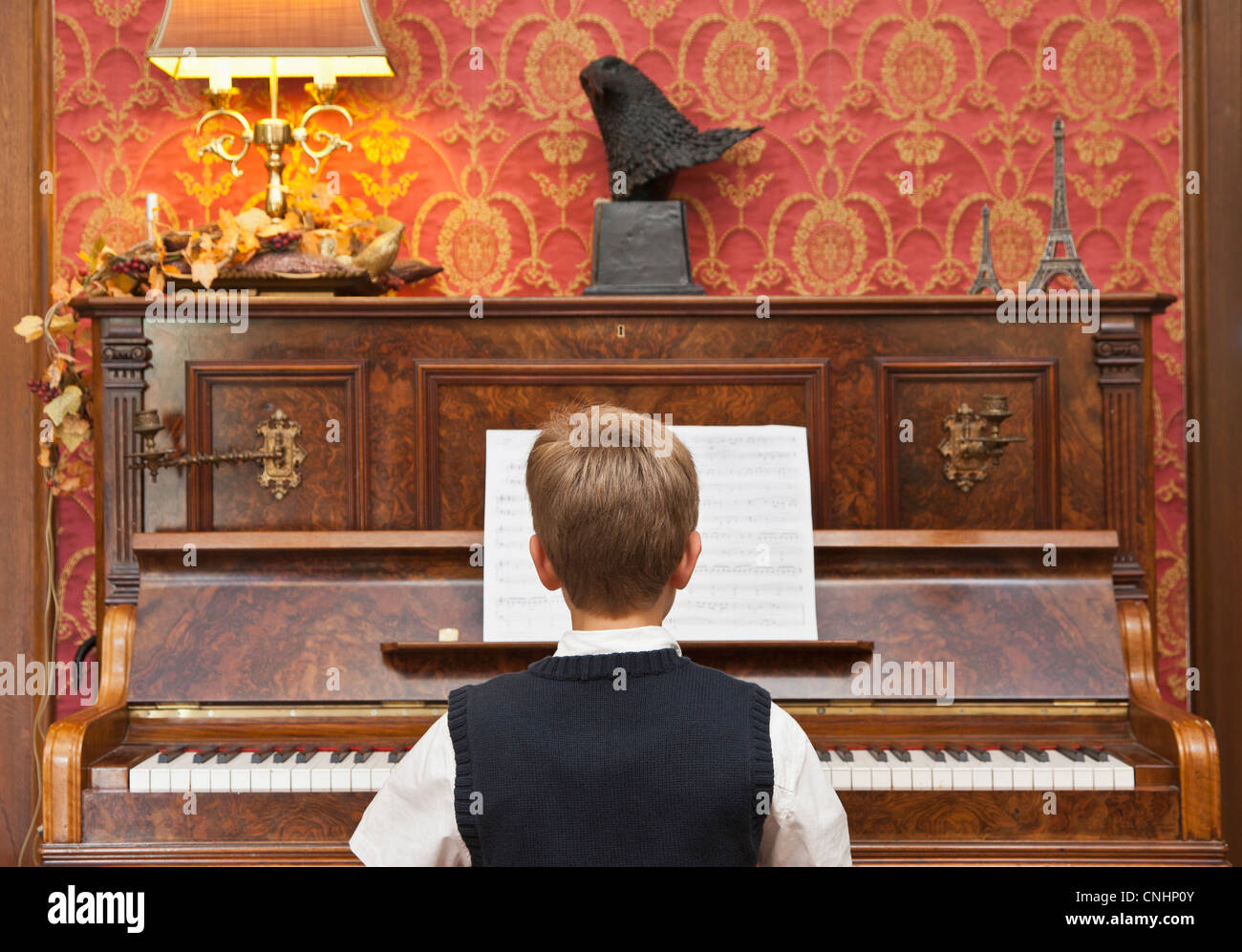 Un ragazzo praticare su un pianoforte verticale Foto Stock