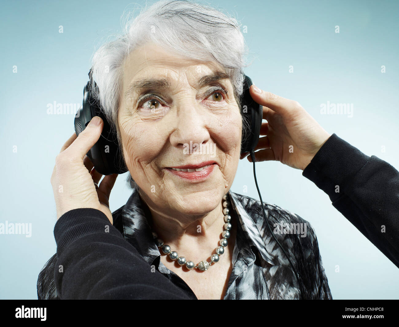 Una persona che mette le cuffie su un senior donna Foto Stock