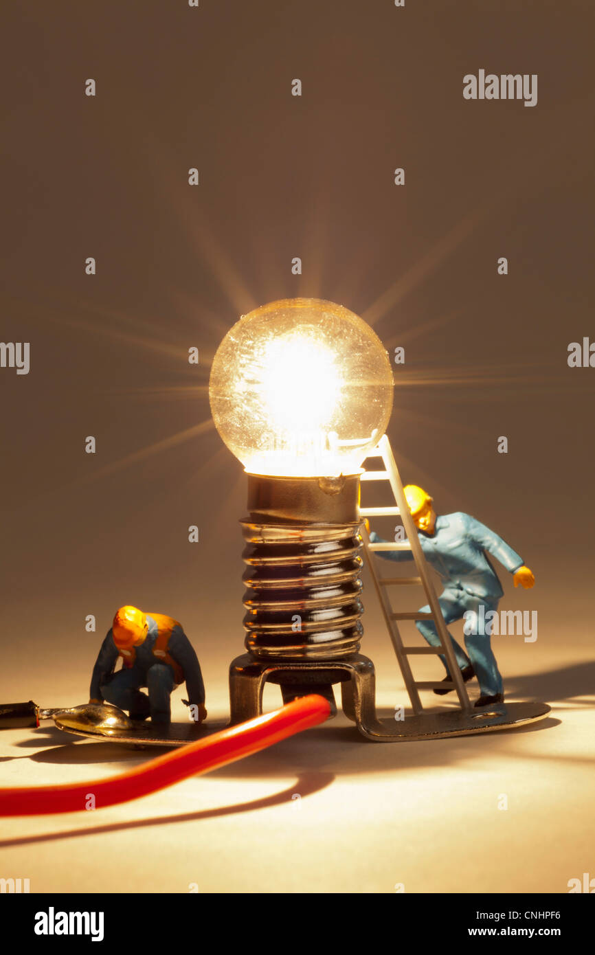 Elettricista in miniatura figurine lavorando su una luce accesa la lampadina Foto Stock