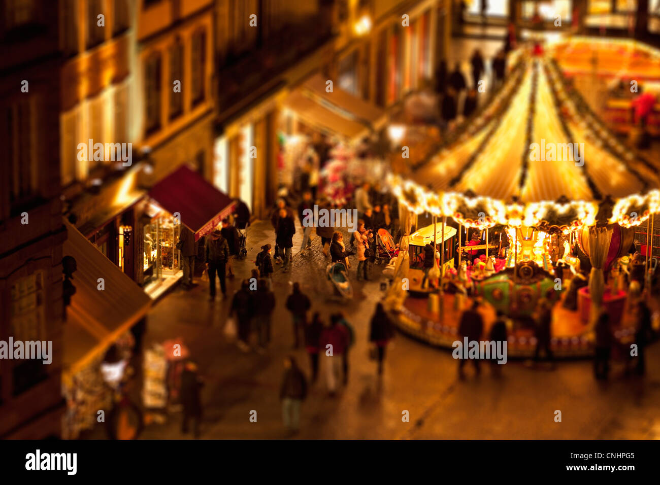 Tilt-shift di una folla di persone ad una giostra a un festival all'aperto, Strasburgo, Francia Foto Stock