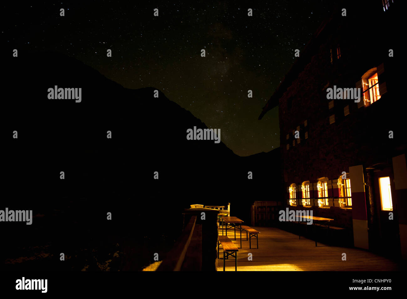 Un edificio illuminato contro un profilarsi di montagna e cielo stellato Foto Stock