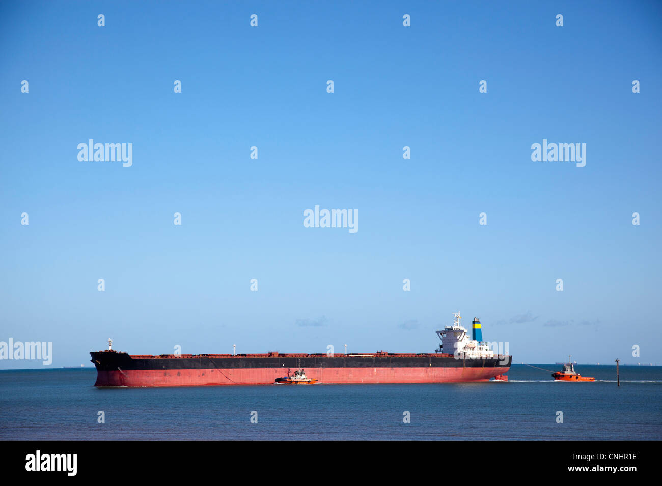 Un rimorchiatore a traino tirando una nave da trasporto merci Foto Stock