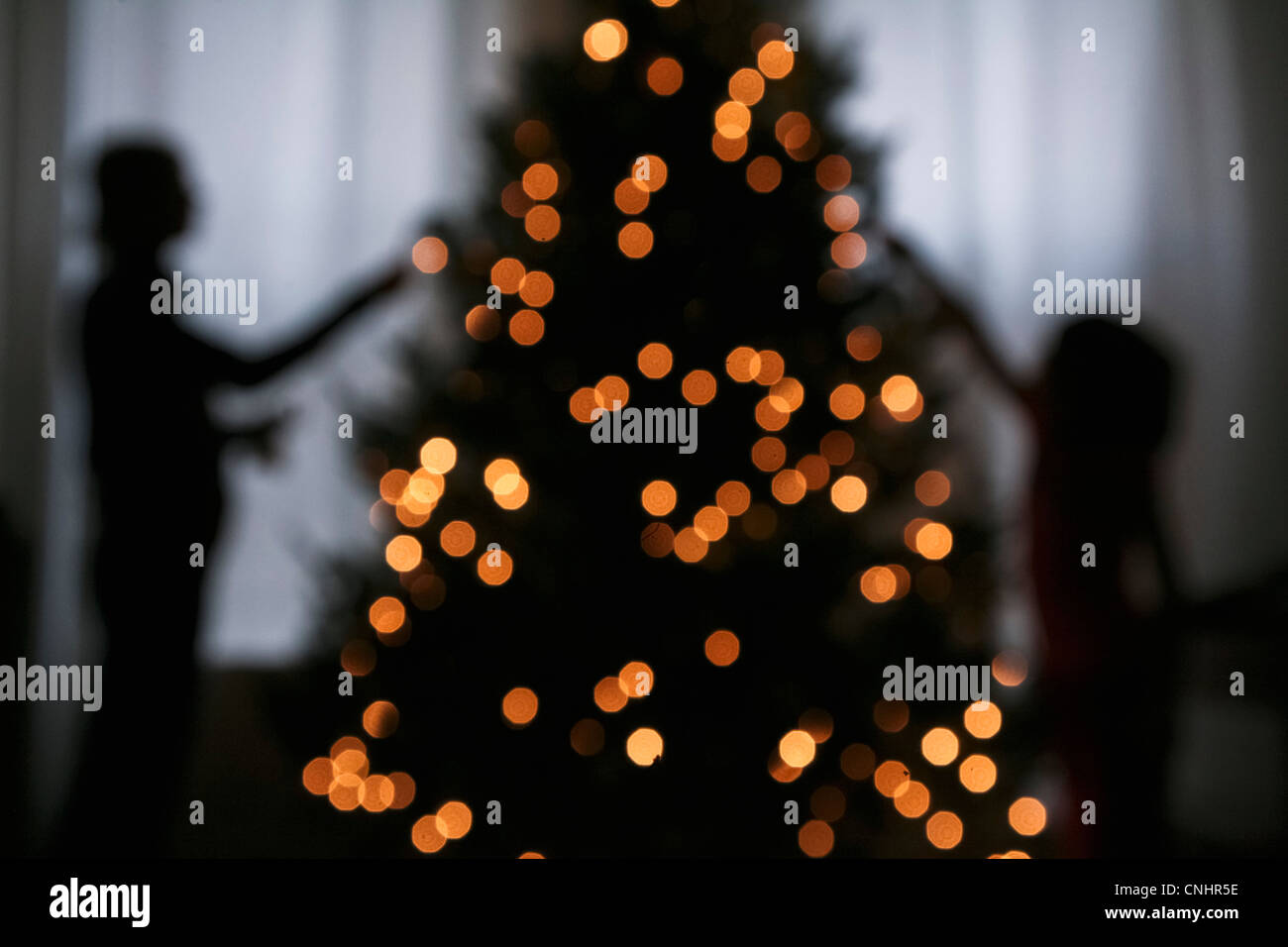 Silhouette di madre e figlia decorare un albero di Natale Foto Stock