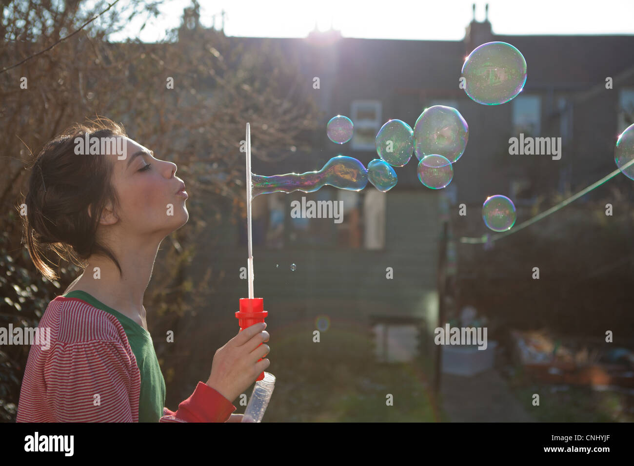 Giovane donna a soffiare bolle all'aperto Foto Stock