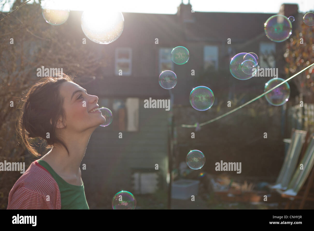 Giovane donna all'aperto con bolle galleggianti in aria Foto Stock