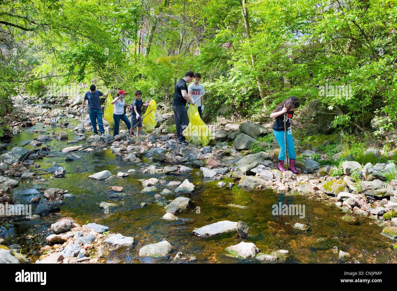 La giornata della terra famiglia ispanica pulisce l'immondizia nel cestino della spazzatura da un torrente nel Maryland USA Foto Stock