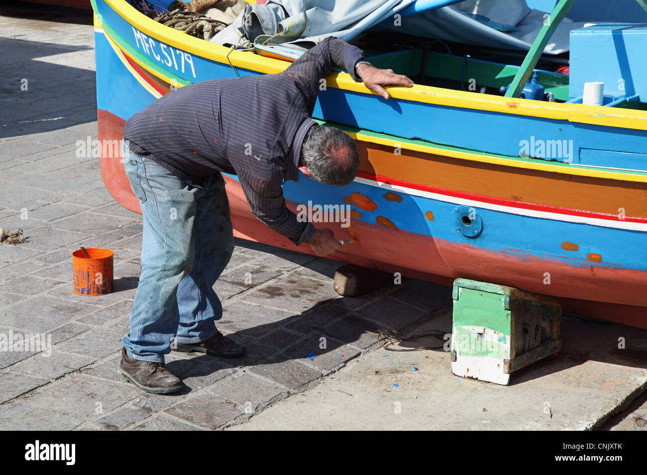Fisherman dipinto il suo vivace la barca di legno del porto di Marsaxlokk, Malta, Europa Foto Stock