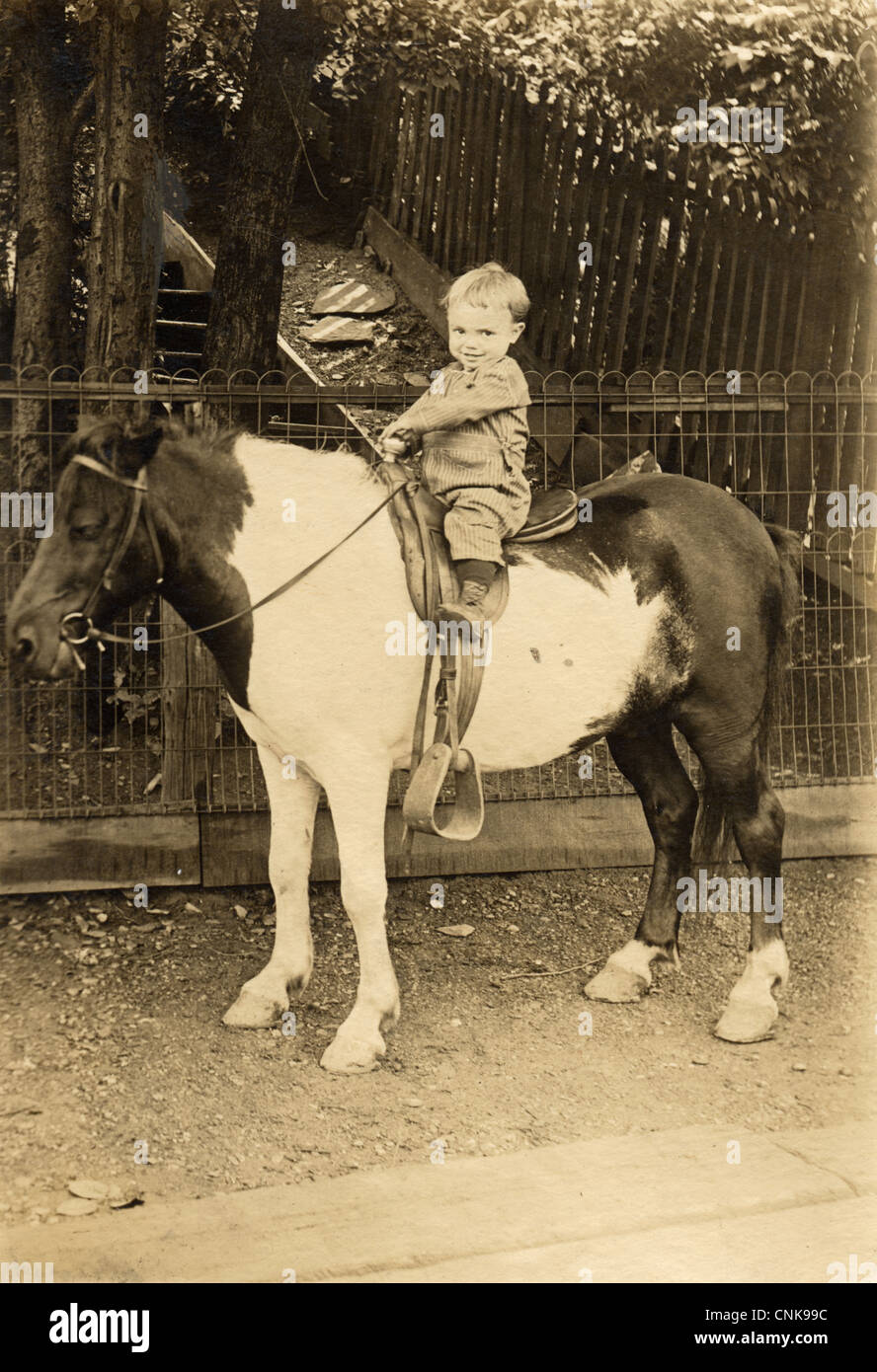 Molto piccolo ragazzo a cavallo di un pony a casa sua Foto Stock