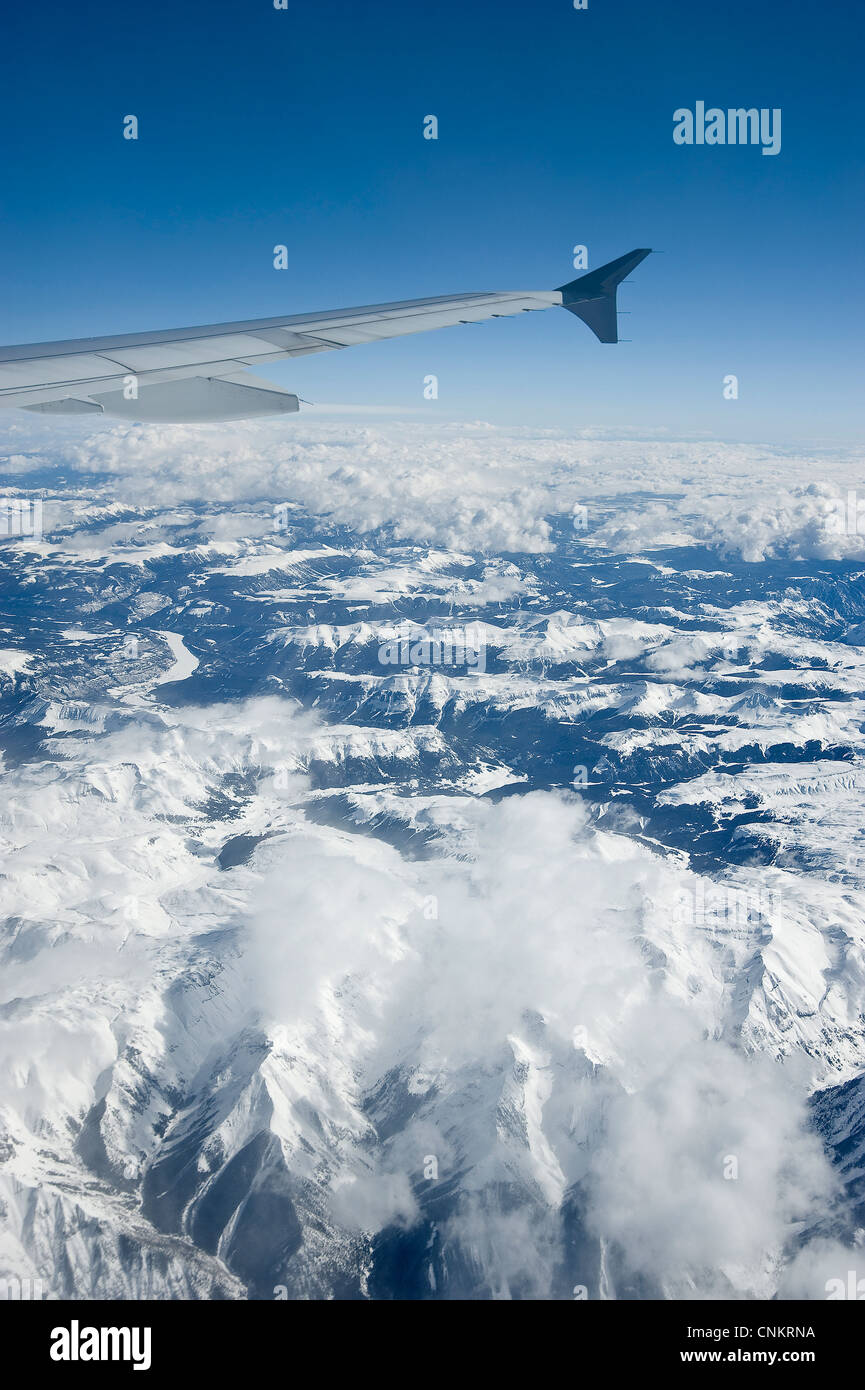 Ala di aeroplano con il blu del cielo e le montagne al di sotto di Foto Stock