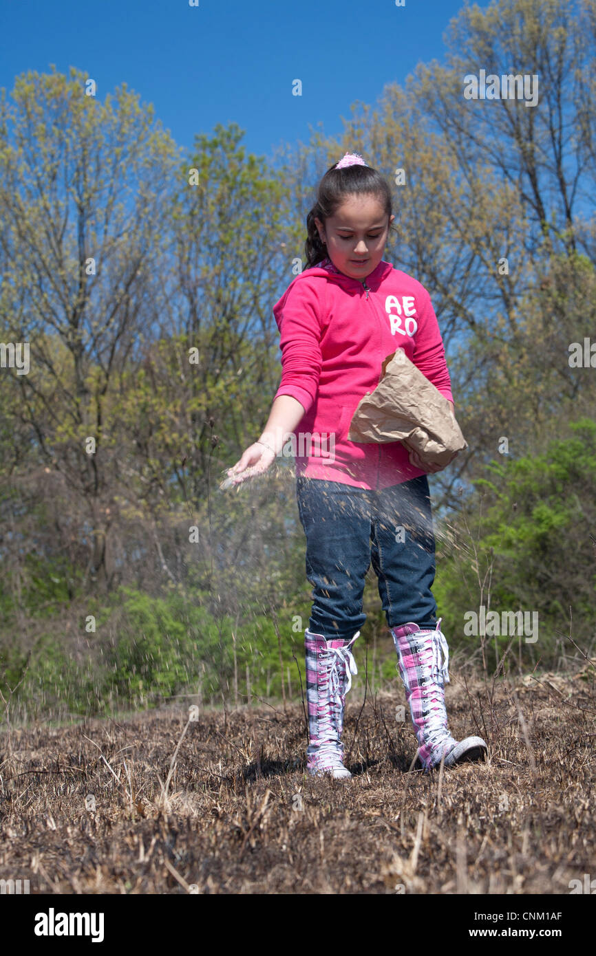 I bambini delle elementari seminare i semi per ripristinare la prateria nativi dopo che esso è stato intenzionalmente bruciata per eliminare le specie invasive. Foto Stock