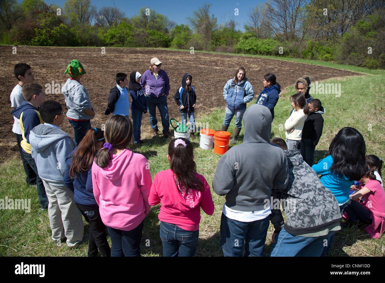 I bambini delle elementari preparare per seminare i semi per ripristinare un nativo di prateria dopo che esso è stato intenzionalmente bruciati. Foto Stock