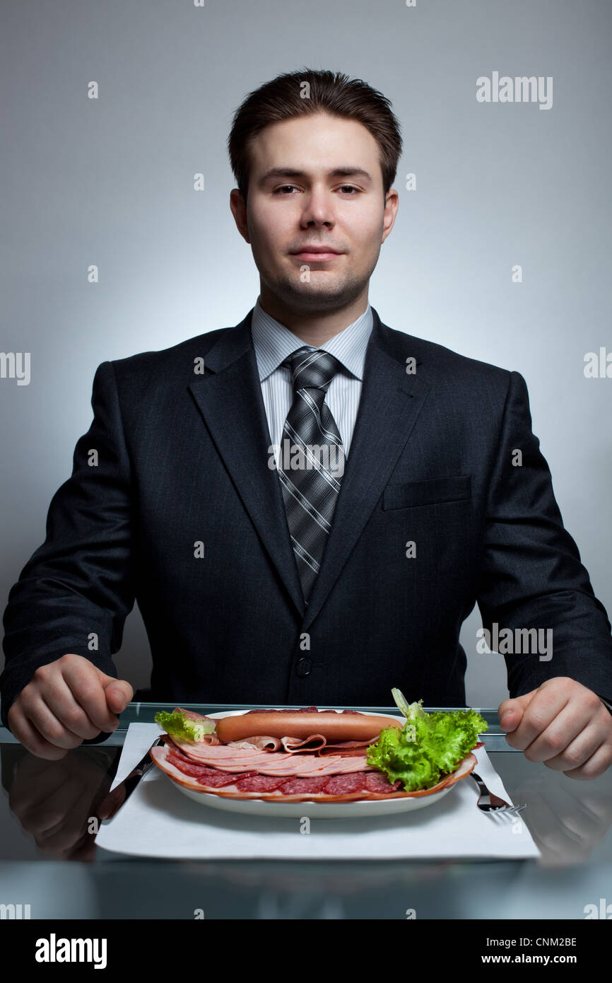Giovane imprenditore mangiare. Ricco menu a base di carne. Foto Stock