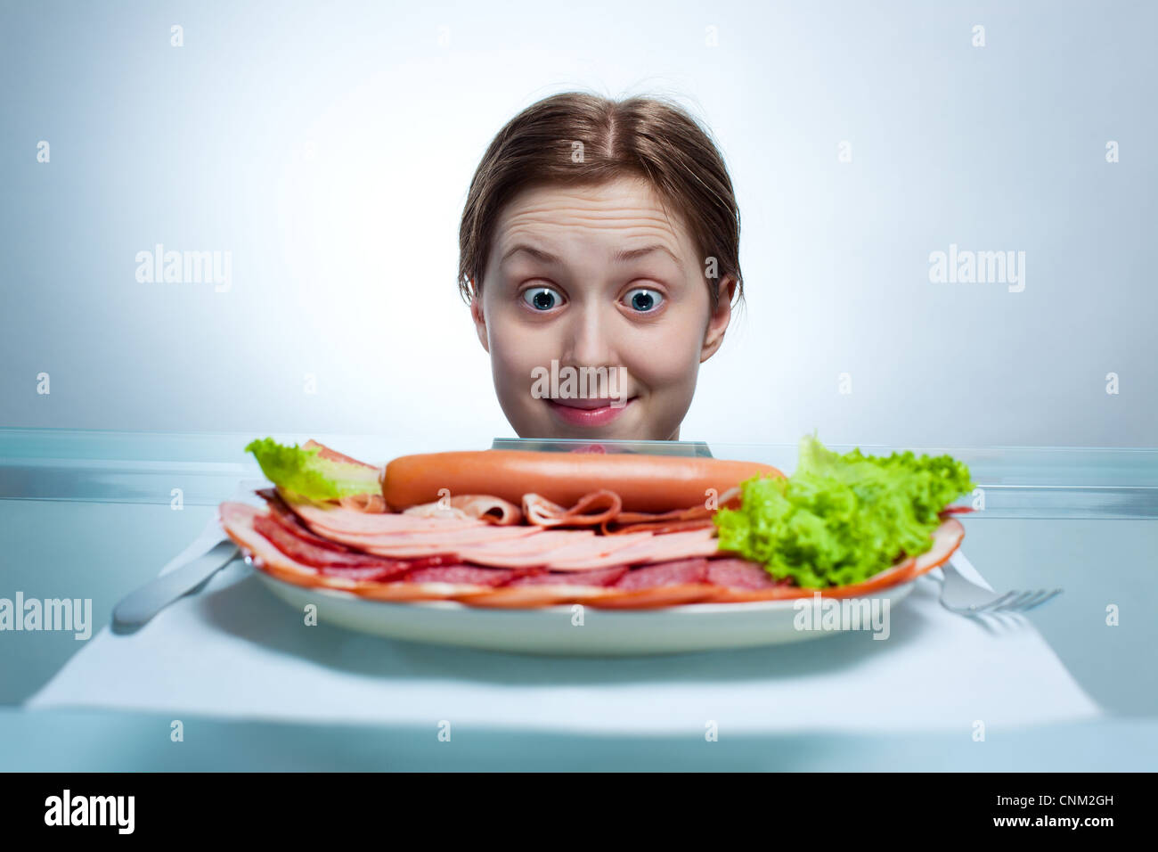 Giovane donna che guarda sulla piastra con ricchi menù a base di carne. Foto Stock