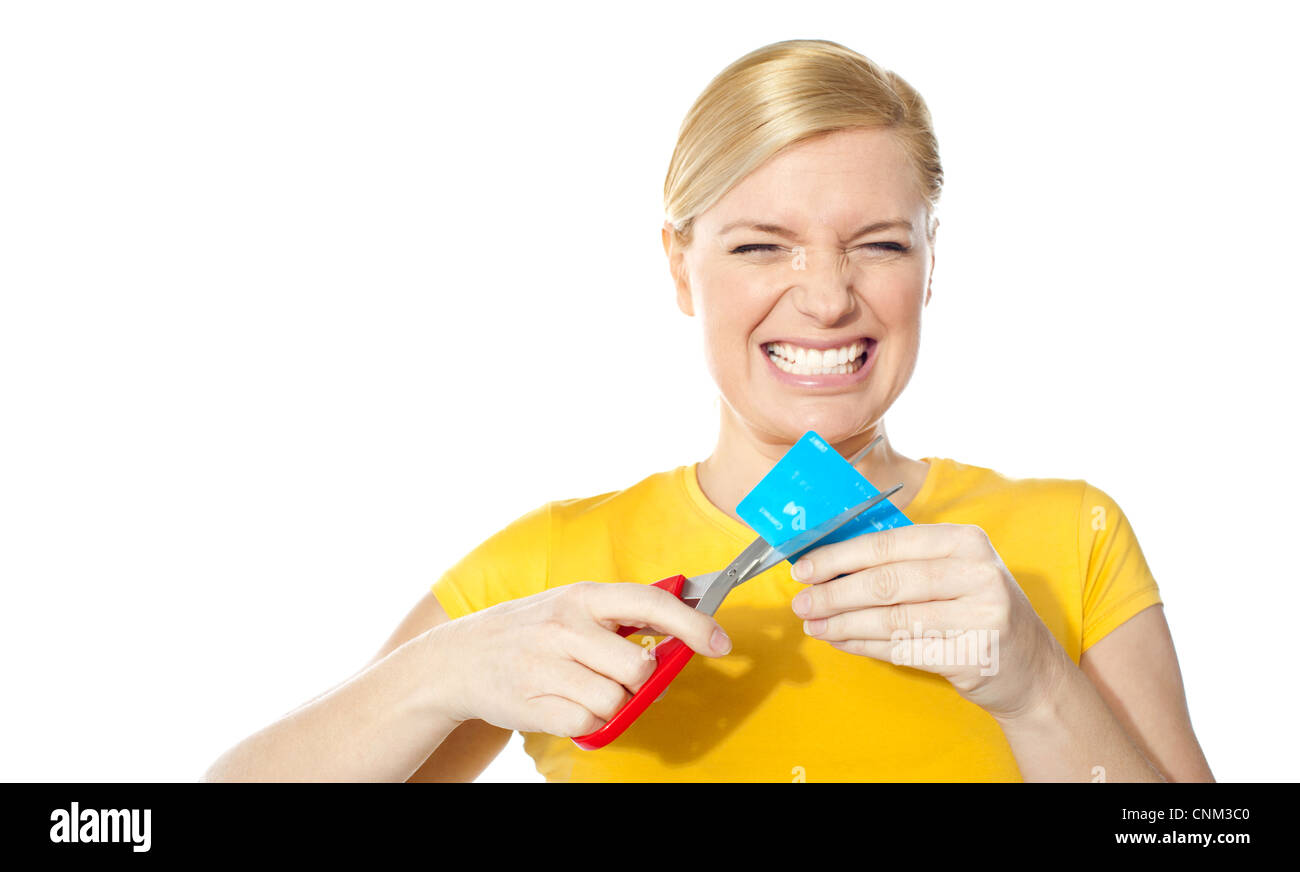 La donna il digrignamento dei denti durante il taglio la sua carta di credito isolato su bianco Foto Stock