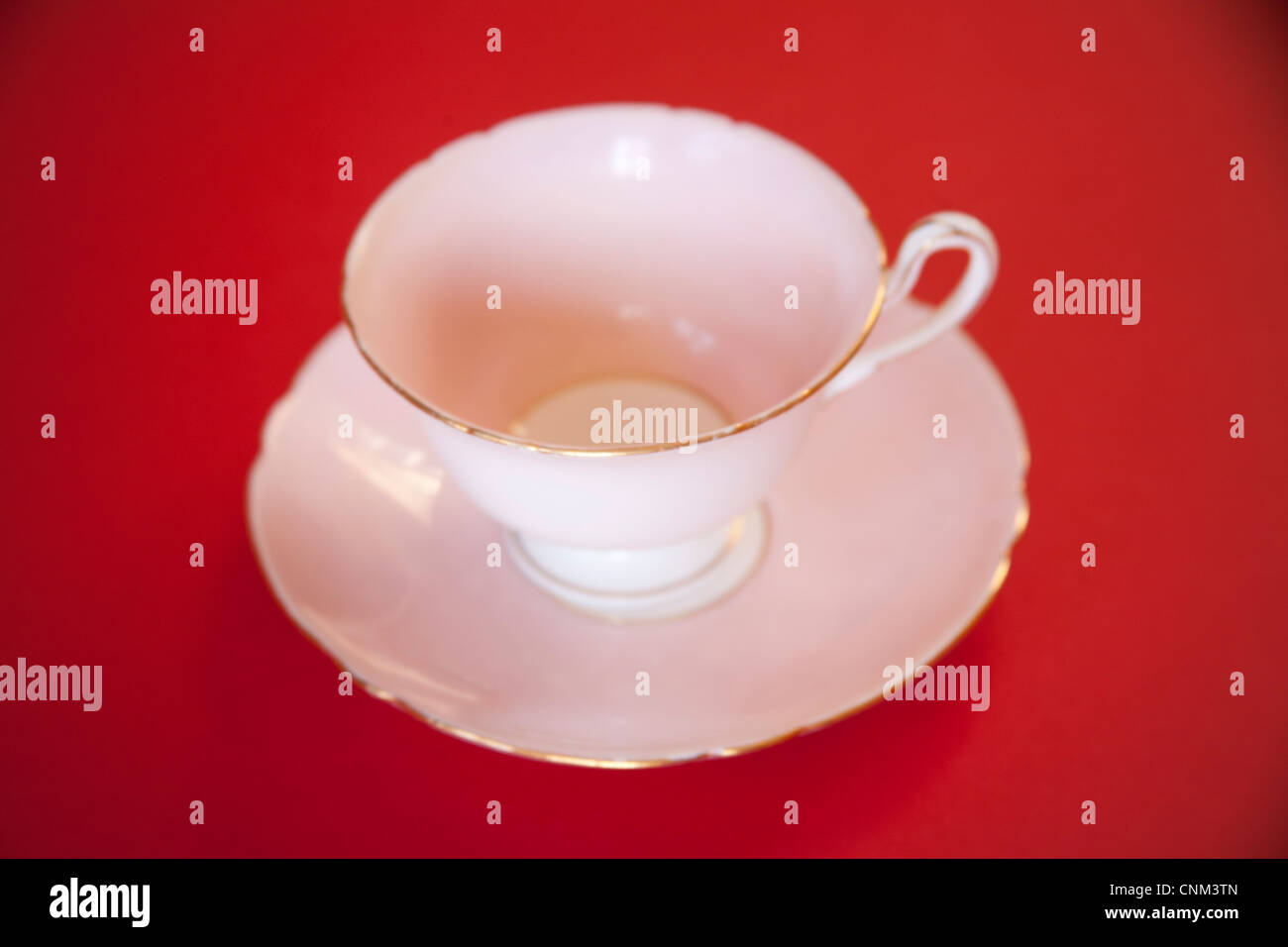 Rosa cina tazza da caffè con piattino con rivestimento in oro su uno sfondo rosso Foto Stock