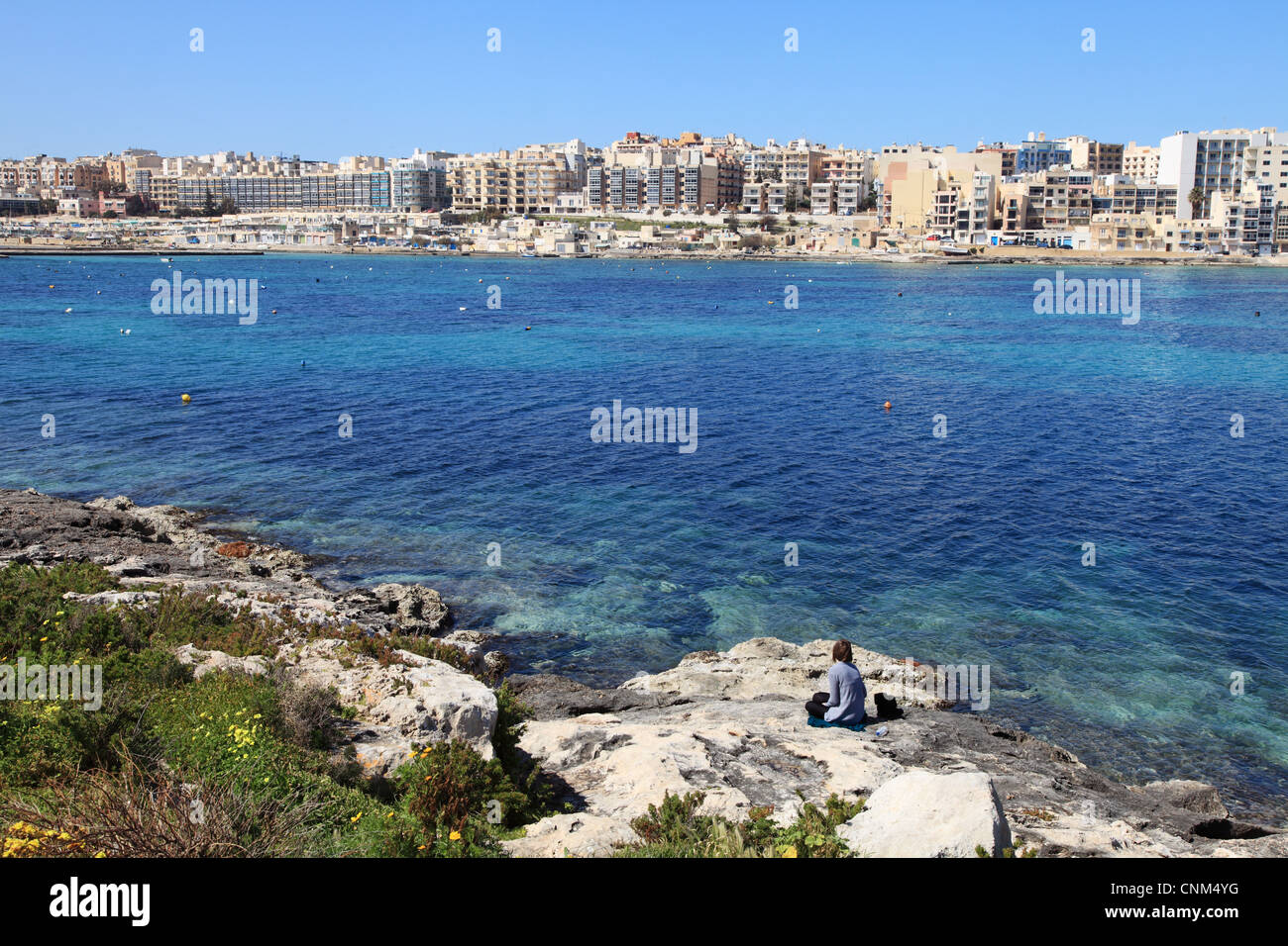 Giovane donna si affaccia sull'estuario verso il turista alberghi a Qawra Malta, Europa Foto Stock