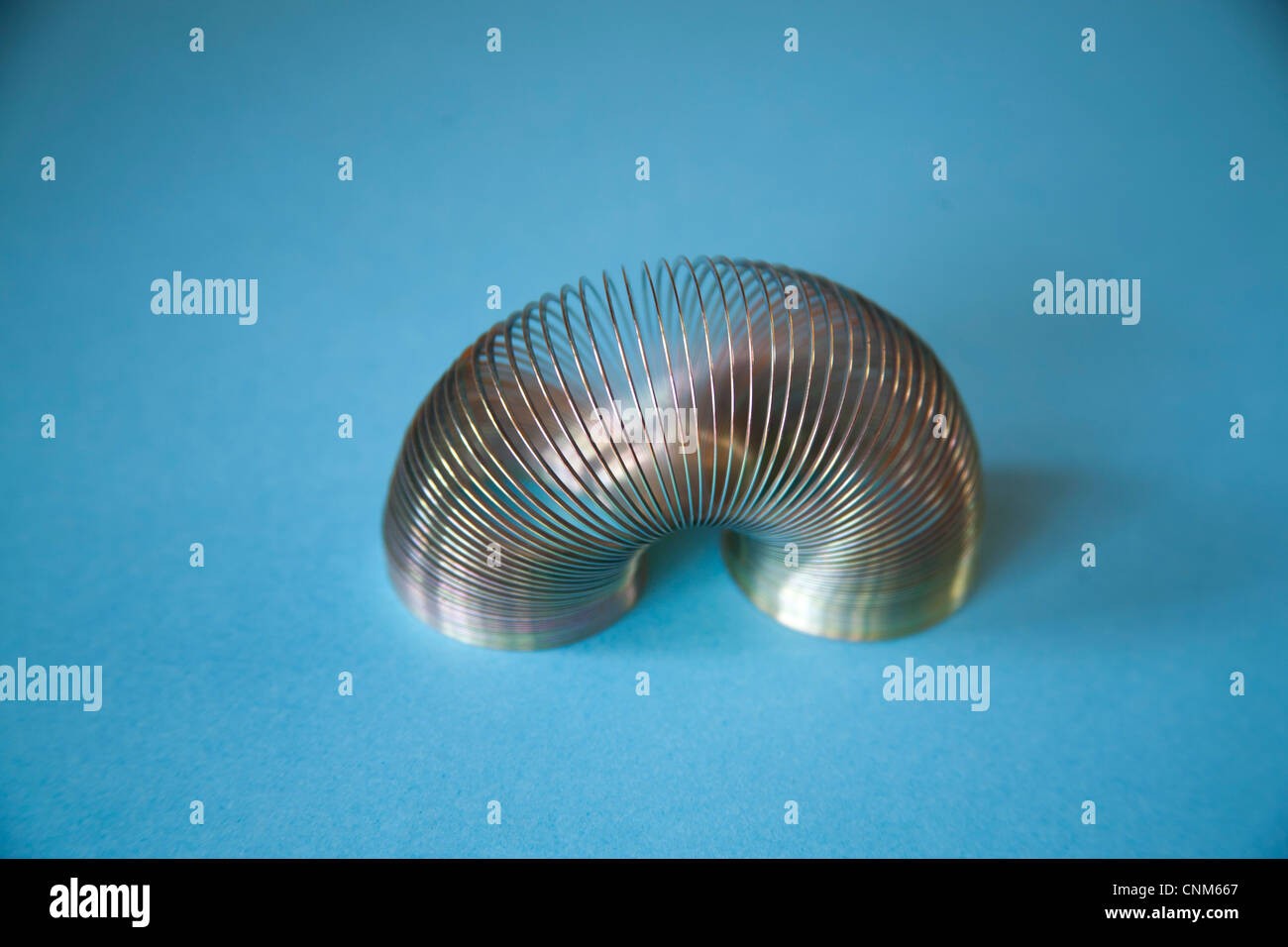 Slinky o pigro giocattolo a molla costituito da una molla elicoidale che si allunga e può oscillare in alto e in basso Foto Stock