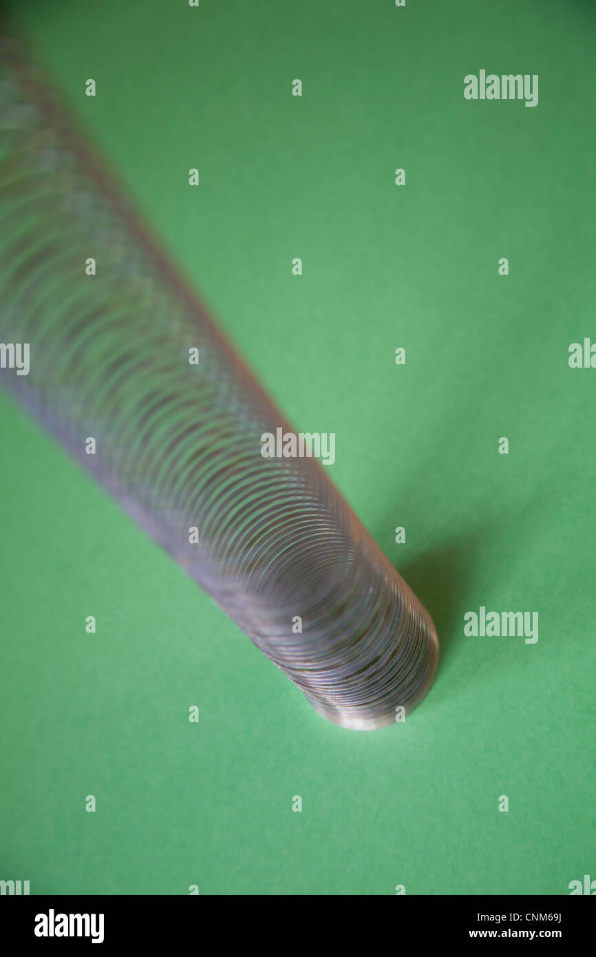 Slinky o pigro giocattolo a molla costituito da una molla elicoidale che si allunga e può oscillare in alto e in basso Foto Stock