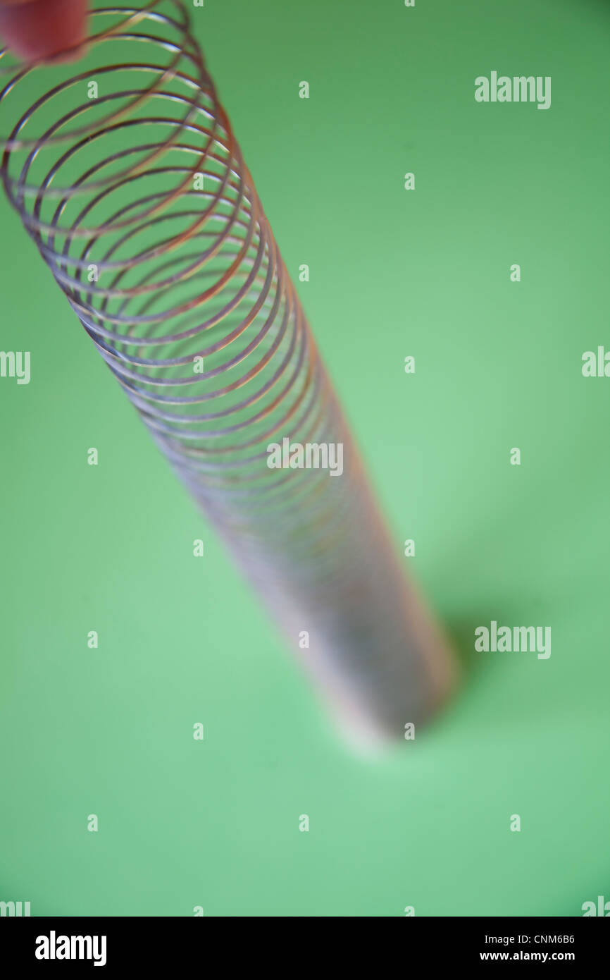 Slinky o pigro giocattolo a molla costituito da una molla elicoidale che si allunga e può oscillare in alto e in basso Foto Stock