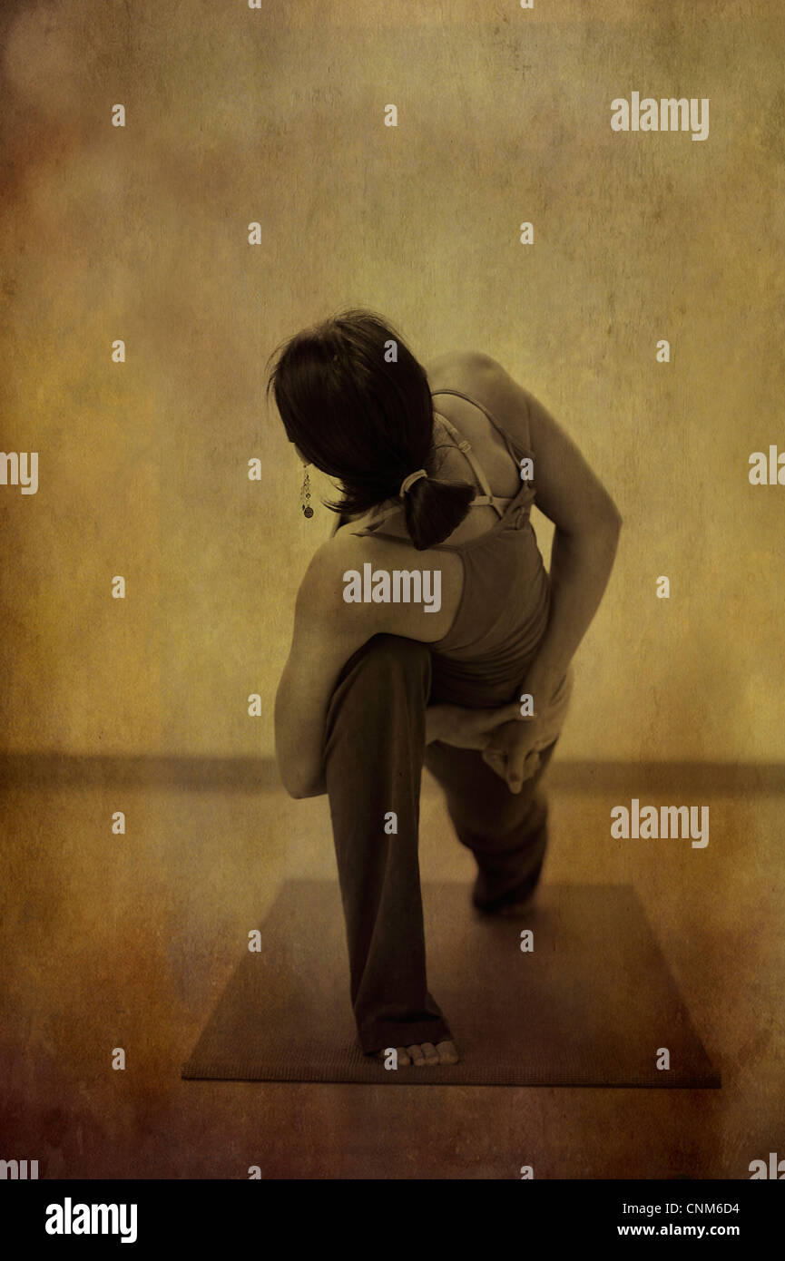 Anonimo dai capelli scuri donna in una profonda twisted legato lo yoga pone all'interno. Foto trattate. Foto Stock