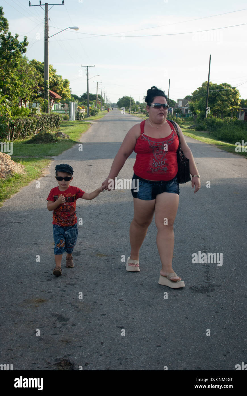 Designer vestito in corrispondenza abbigliamento e occhiali da sole, madre e figlio a piedi Foto Stock